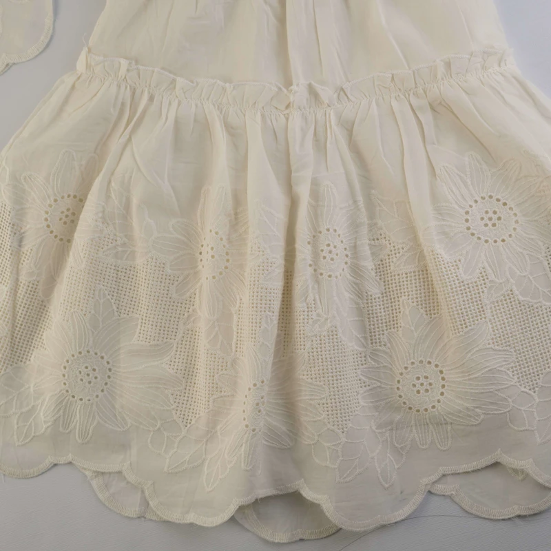 نمای نزدیک از طرح گل‌های خامه دوزی و لبه دالبری لباس کودک