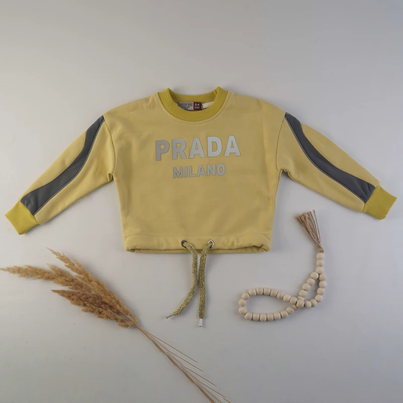 نمای نزدیک از چاپ برند Prada روی بلوز دورس کودکانه