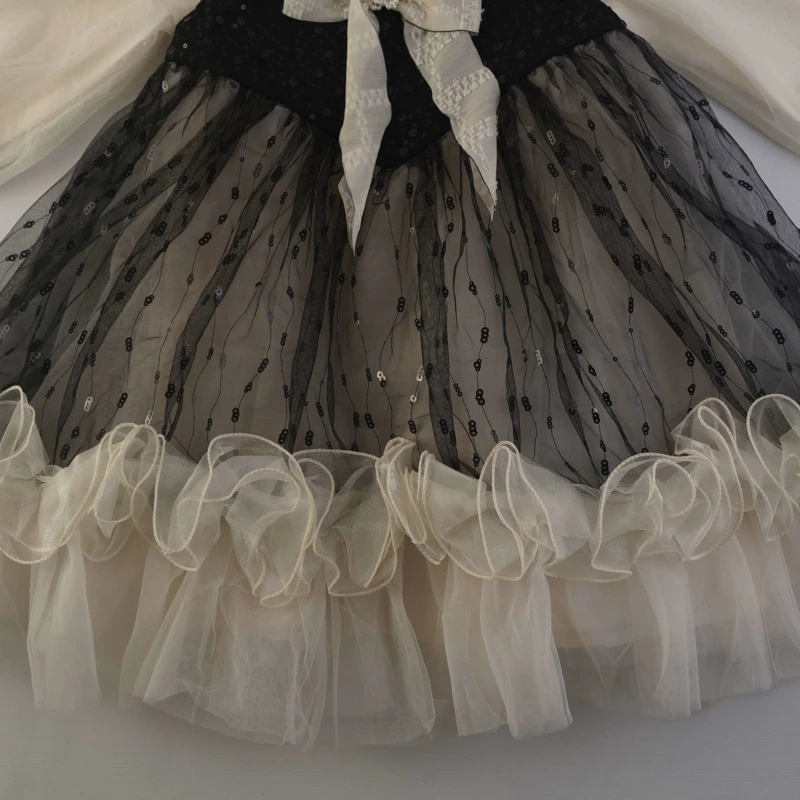 نمای تور پولک‌دوزی شده و لبه‌های چین‌دار دامن لباس دخترانه
