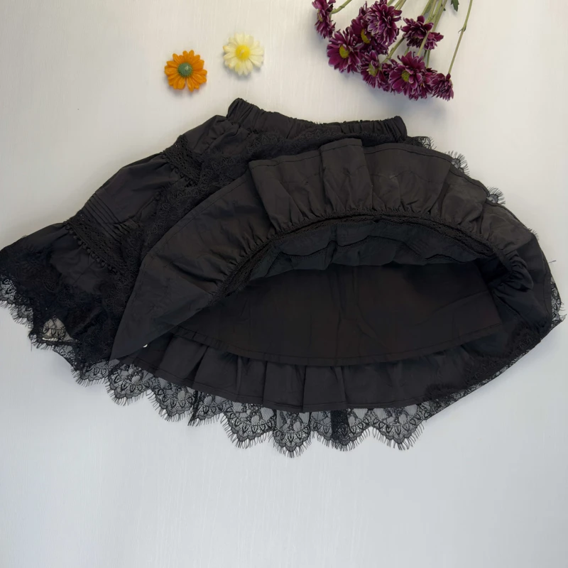 نمای نزدیک از گیپور مژه‌دار و دوخت‌های پلیسه روی دامن مشکی بچگانه.