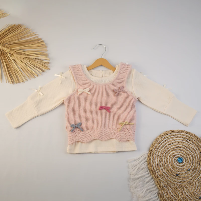 ست دخترانه شامل بلوز کرم و جلیقه بافت صورتی پاپیون‌دار