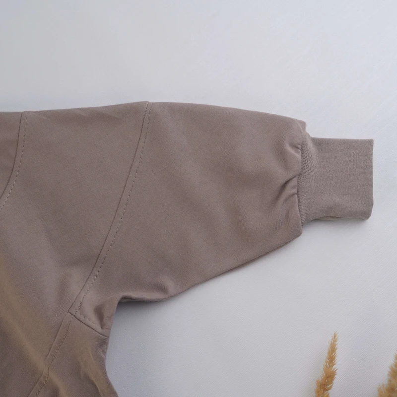 نمای نزدیک گلدوزی فانتزی ون و گل‌های رنگی روی لباس کودک