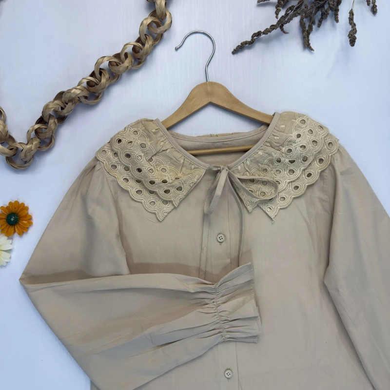 نمای نزدیک یقه خامه دوزی شده و دکمه‌های شومیز دخترانه نسکافه‌ای