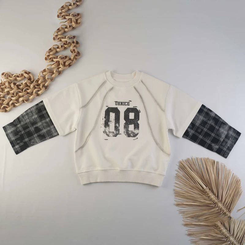 نمای جلوی دورس بچگانه کرم با آستین چهارخانه سیاه و سفید