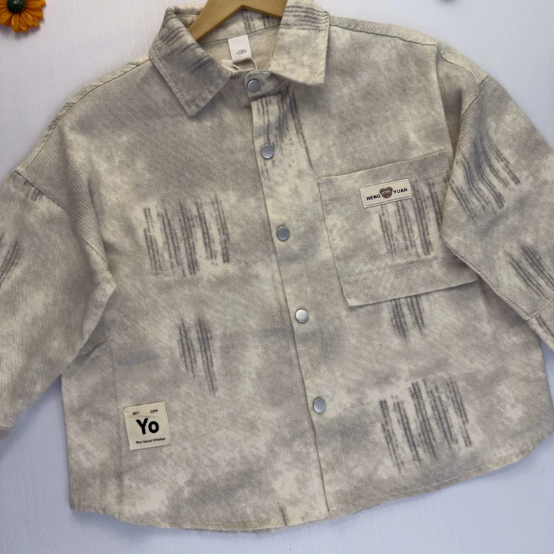 نمای نزدیک از بافت پارچه کبریتی ریز و طرح پتینه طوسی روی پیراهن